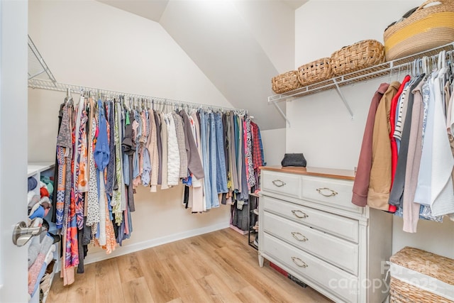 walk in closet with light wood-type flooring and lofted ceiling
