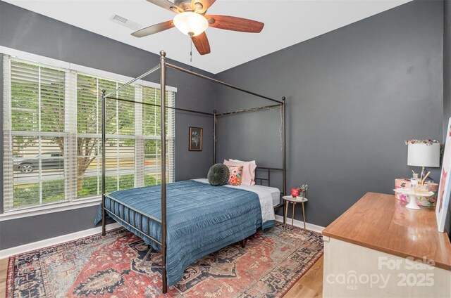 bedroom featuring ceiling fan, baseboards, wood finished floors, and visible vents