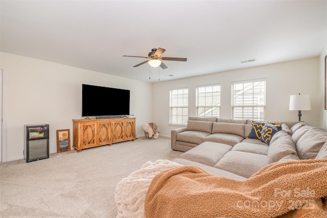 living area featuring baseboards, visible vents, ceiling fan, and light colored carpet