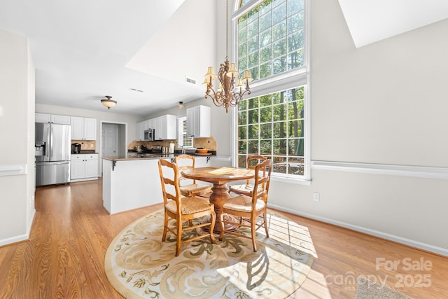 14812 Stonegreen Ln, Huntersville, NC 28078 - dining area featuring a chandelier, a towering ceiling, light wood finished floors, baseboards, and visible vents