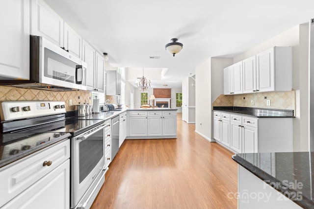 14812 Stonegreen Ln, Huntersville, NC 28078 - kitchen featuring a peninsula, light wood-type flooring, backsplash, a notable chandelier, and appliances with stainless steel finishes