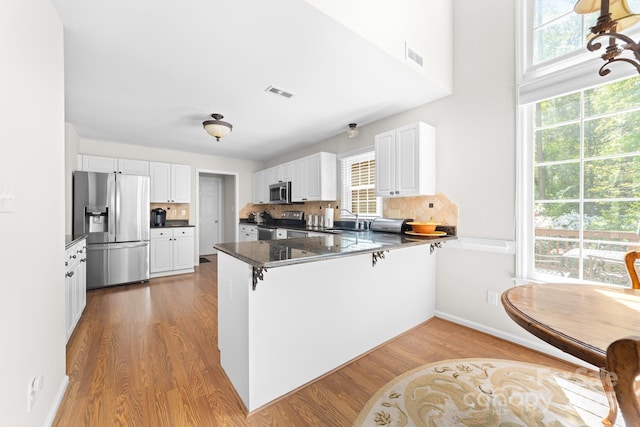 14812 Stonegreen Ln, Huntersville, NC 28078 - kitchen with wood finished floors, a sink, a peninsula, appliances with stainless steel finishes, and visible vents