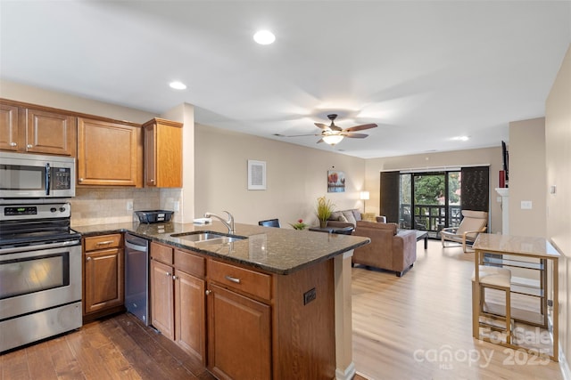 9029 J M Keynes Dr Unit 63, Charlotte, NC 28262 - kitchen with stainless steel appliances, wood finished floors, a sink, and brown cabinetry