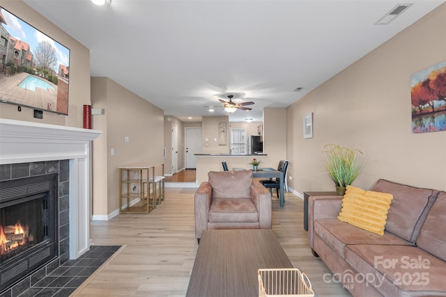 9029 J M Keynes Dr Unit 63, Charlotte, NC 28262 - living area with light wood-style floors, ceiling fan, a tile fireplace, baseboards, and visible vents