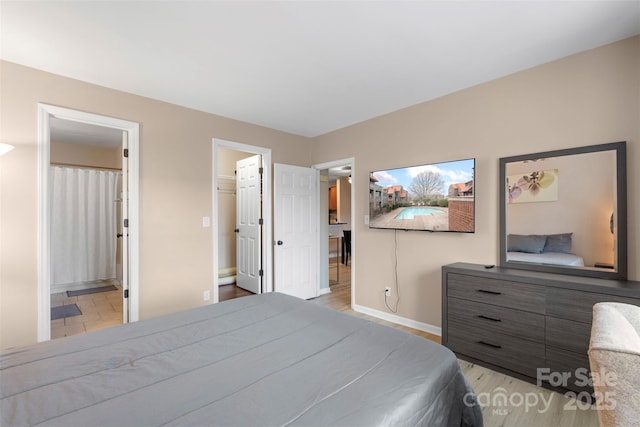 9029 J M Keynes Dr Unit 63, Charlotte, NC 28262 - bedroom featuring baseboards, ensuite bathroom, and light wood-type flooring