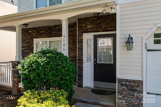 doorway to property with covered porch and stone siding