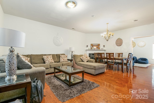 living area featuring visible vents, wood finished floors, and a notable chandelier