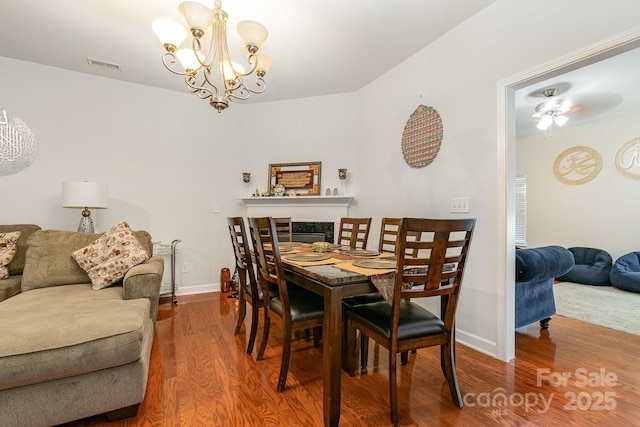 dining room with a high end fireplace, baseboards, wood finished floors, and visible vents
