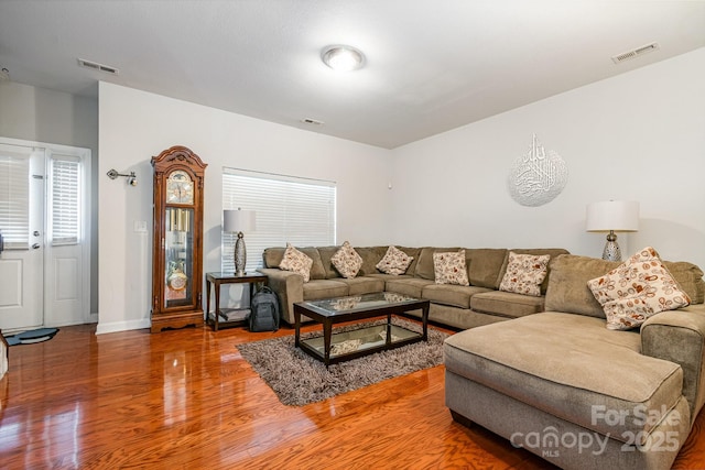 living area with baseboards, visible vents, and wood finished floors