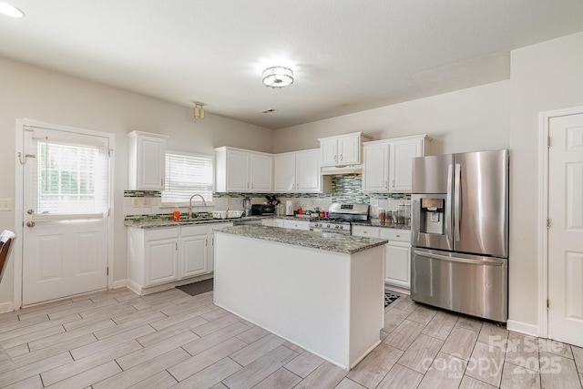 kitchen with appliances with stainless steel finishes, backsplash, under cabinet range hood, and white cabinetry