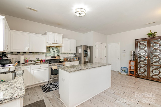 kitchen with a kitchen island, visible vents, tasteful backsplash, wood finish floors, and stainless steel appliances
