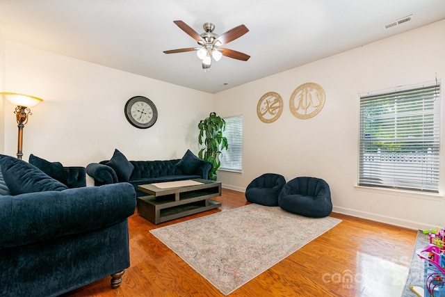 living area featuring a ceiling fan, wood finished floors, and a healthy amount of sunlight