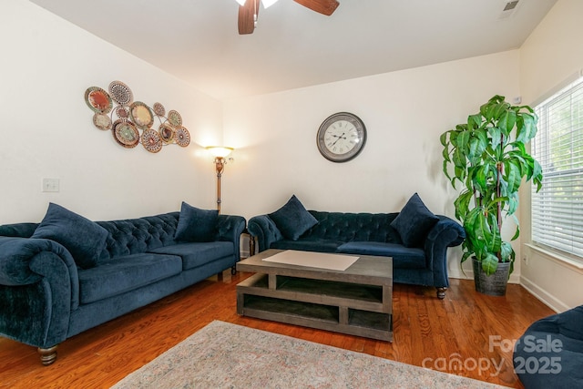 living area with visible vents, a ceiling fan, baseboards, and wood finished floors