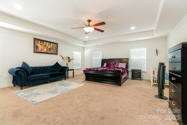 bedroom featuring a tray ceiling, light carpet, and baseboards