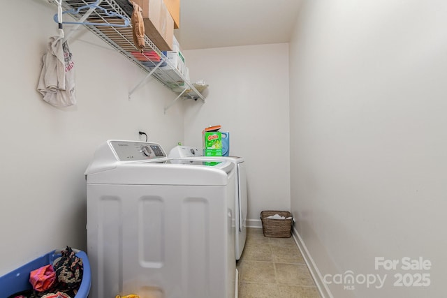 clothes washing area featuring washer and dryer, light tile patterned flooring, laundry area, and baseboards