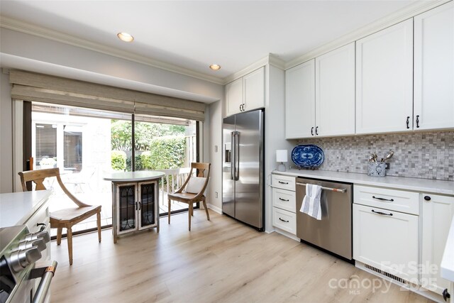 5128 Dunes Ct, Charlotte, NC 28226 - kitchen featuring stainless steel appliances, ornamental molding, light countertops, decorative backsplash, and light wood finished floors