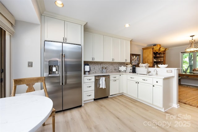 5128 Dunes Ct, Charlotte, NC 28226 - kitchen with stainless steel appliances, light wood-style flooring, a peninsula, ornamental molding, and tasteful backsplash