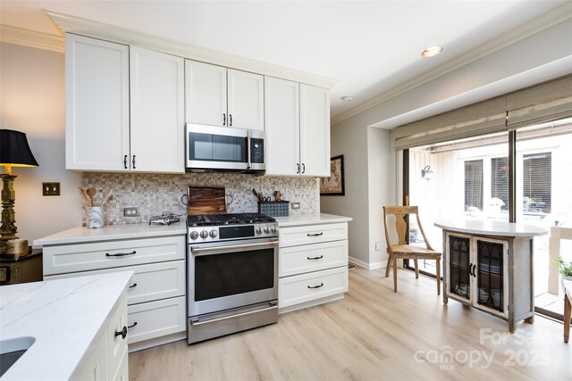 5128 Dunes Ct, Charlotte, NC 28226 - kitchen featuring appliances with stainless steel finishes, ornamental molding, light wood finished floors, decorative backsplash, and white cabinetry