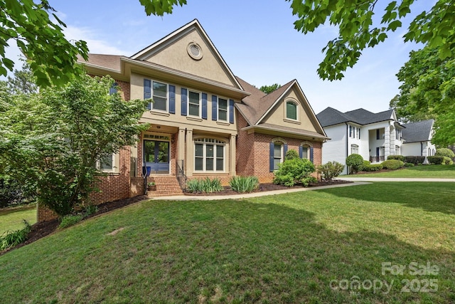 view of front of property featuring stucco siding, a front lawn, and brick siding