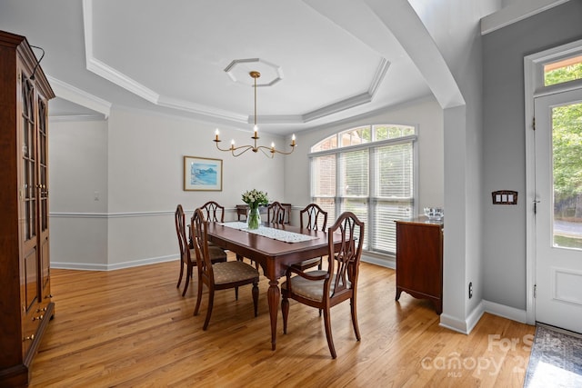 dining room featuring baseboards, a notable chandelier, light wood-style floors, ornamental molding, and a tray ceiling