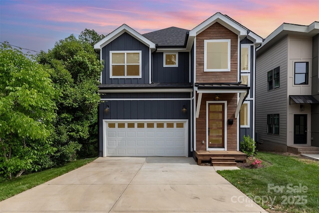 view of front facade featuring board and batten siding, driveway, roof with shingles, a front yard, and a garage