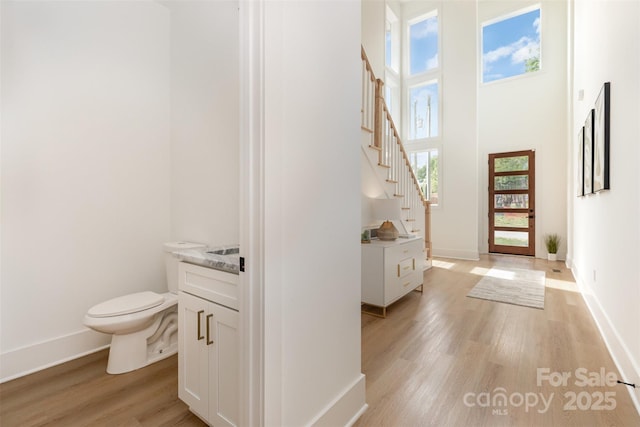foyer featuring stairs, baseboards, a wealth of natural light, and light wood-style floors