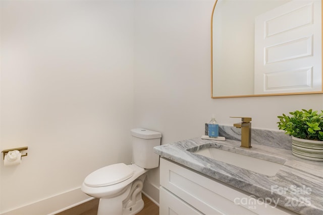 bathroom featuring baseboards, toilet, vanity, and wood finished floors