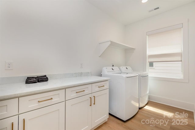 laundry room with light wood-style floors, cabinet space, washing machine and dryer, baseboards, and visible vents