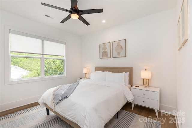 bedroom featuring wood finished floors, visible vents, a ceiling fan, and baseboards