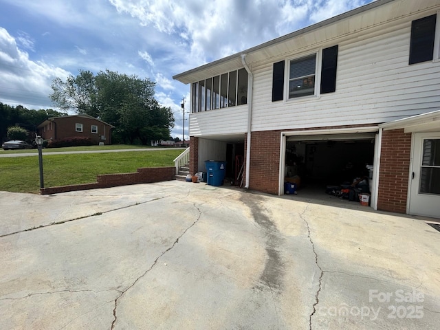 201 Mitchell St, Belmont, NC 28012 - view of side of home featuring a lawn, driveway, a garage, brick siding, and a sunroom
