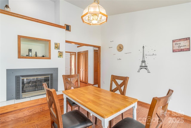 196 Timberline Dr, Maggie Valley, NC 28751 - dining area featuring wood finished floors, a chandelier, a glass covered fireplace, baseboards, and visible vents