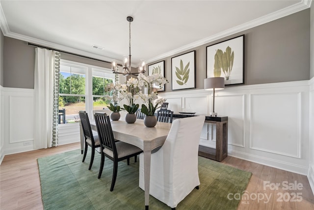 424 Balboa St, Matthews, NC 28104 - dining space featuring a decorative wall, ornamental molding, a chandelier, wood finished floors, and a wainscoted wall