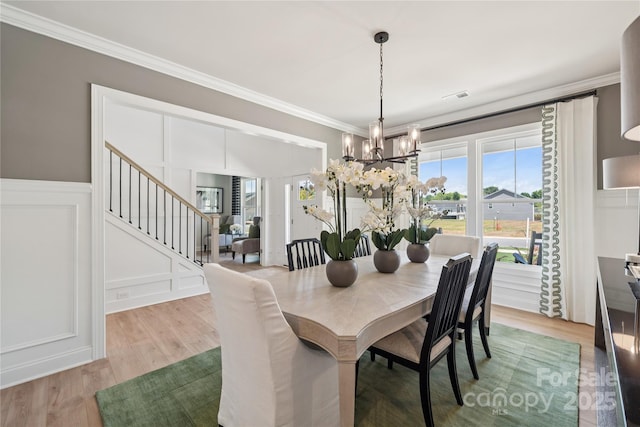 424 Balboa St, Matthews, NC 28104 - dining area featuring a chandelier, stairway, ornamental molding, a decorative wall, and wood finished floors