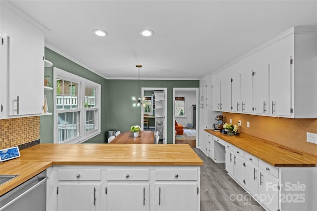 2418 Ainsdale Rd, Charlotte, NC 28226 - kitchen featuring butcher block countertops, white cabinets, a peninsula, backsplash, and ornamental molding