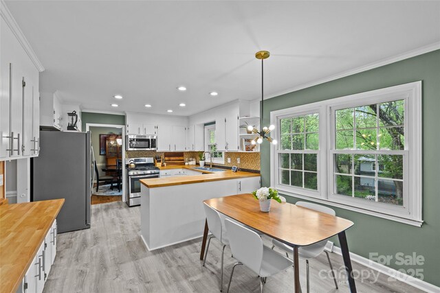 2418 Ainsdale Rd, Charlotte, NC 28226 - kitchen featuring butcher block countertops, appliances with stainless steel finishes, crown molding, a peninsula, and backsplash