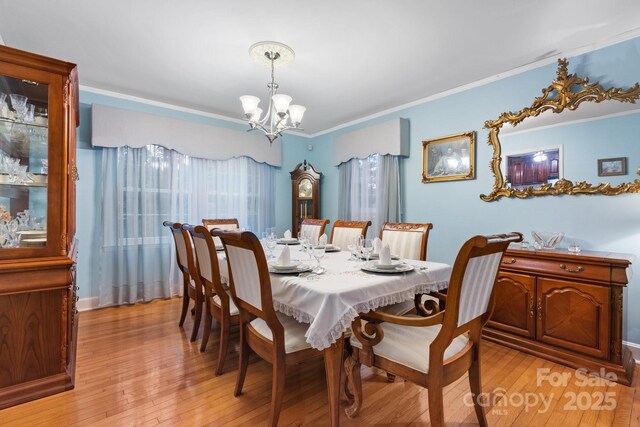 dining room featuring ornamental molding, light wood-style flooring, and a chandelier