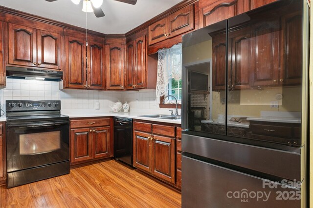 kitchen featuring a ceiling fan, a sink, light countertops, black appliances, and under cabinet range hood