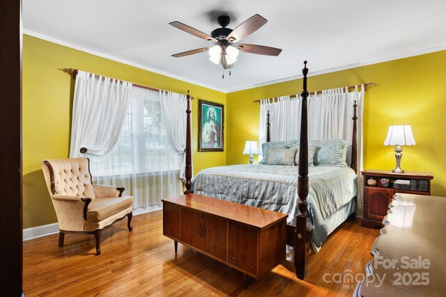 bedroom with baseboards, ceiling fan, ornamental molding, and wood finished floors