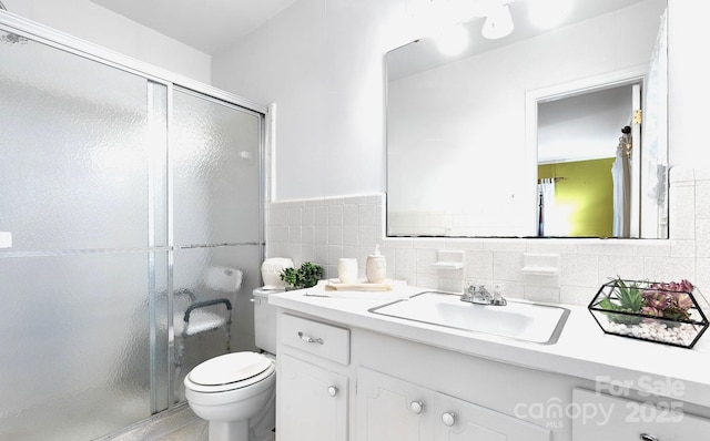 bathroom with vanity, a stall shower, toilet, and tile walls