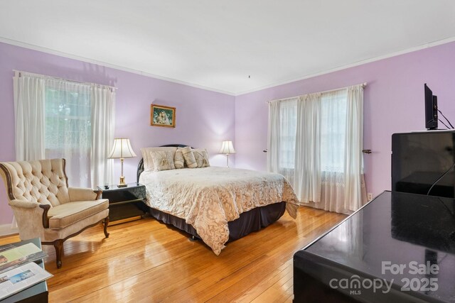 bedroom with crown molding and light wood finished floors