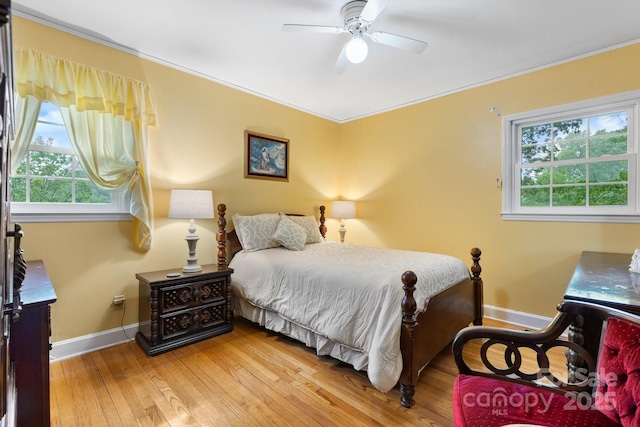 bedroom with baseboards, multiple windows, ceiling fan, and light wood-style floors
