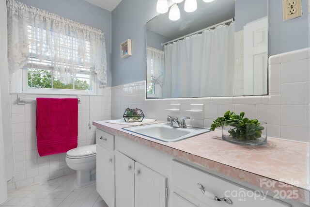 bathroom featuring tile walls, tile patterned flooring, a wainscoted wall, vanity, and toilet