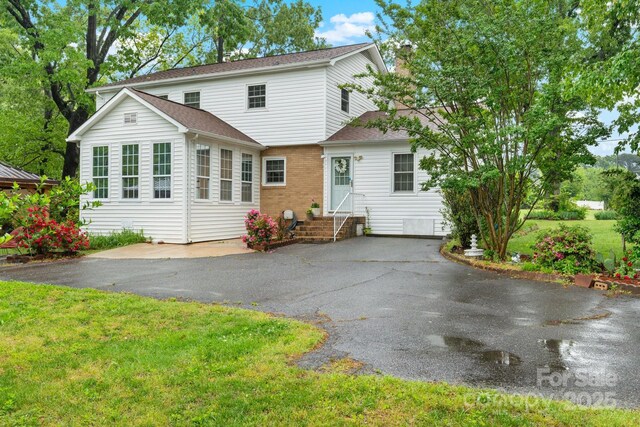 back of house with a shingled roof, a yard, and entry steps