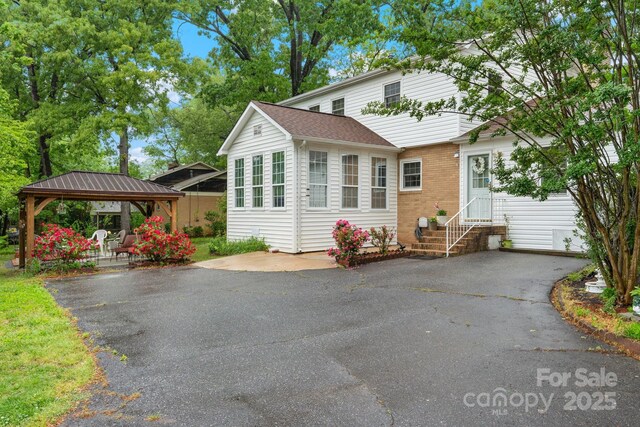 view of front of house featuring brick siding, a gazebo, and entry steps