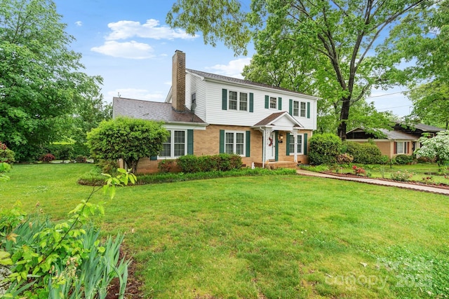 view of front of house featuring a chimney, a front lawn, and brick siding