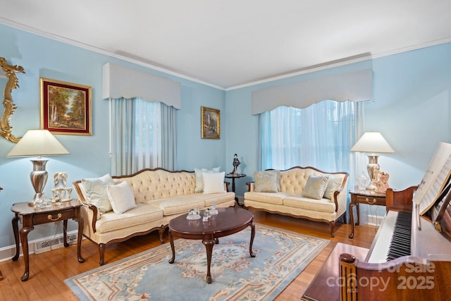 living area featuring crown molding, baseboards, wood finished floors, and visible vents