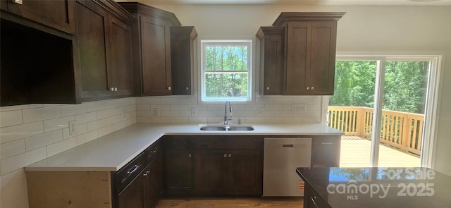 kitchen with decorative backsplash, stainless steel dishwasher, light countertops, and a sink