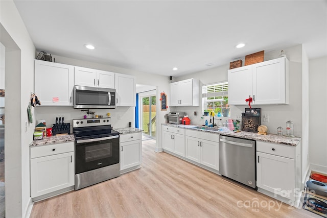 1009 Rainbow Cir, Catawba, SC 29704 - kitchen featuring stainless steel appliances, white cabinets, light wood-type flooring, a sink, and light stone countertops