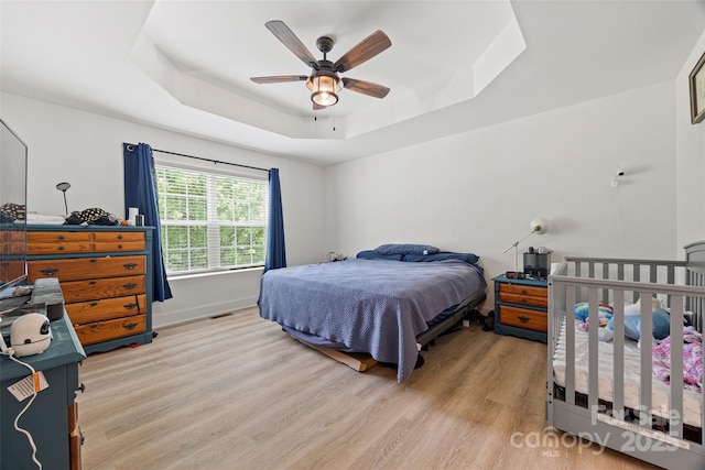1009 Rainbow Cir, Catawba, SC 29704 - bedroom with a tray ceiling, light wood finished floors, and ceiling fan