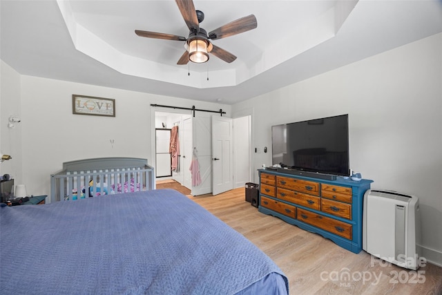 1009 Rainbow Cir, Catawba, SC 29704 - bedroom featuring a raised ceiling, light wood-style flooring, a barn door, and a ceiling fan